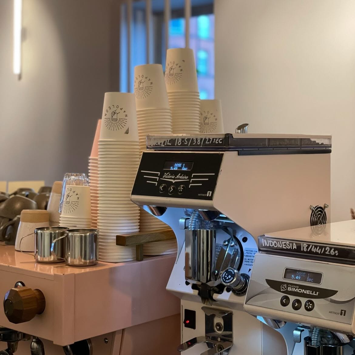 Napoleon's blush-pink espresso machine and grinders, with stacked branded cups