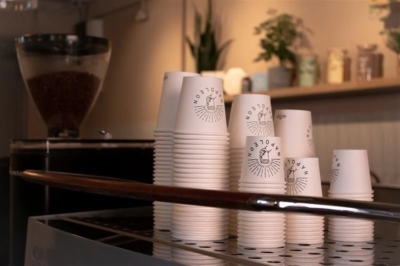 Stacks of Napoleon branded cups beside the grinder